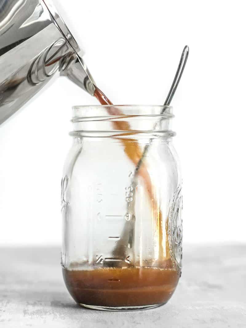 Coffee being poured into a mason jar with caramel