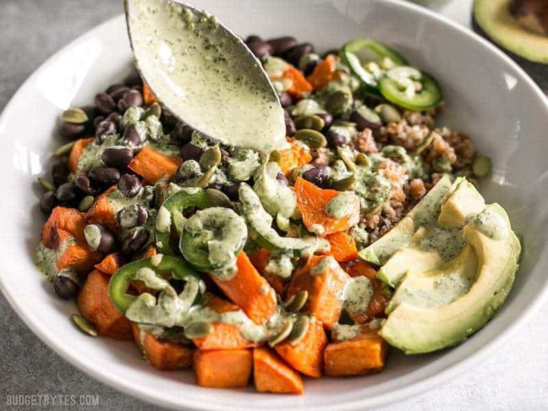 Green Tahini Sauce being drizzled over a Sweet Potato Grain Bowl