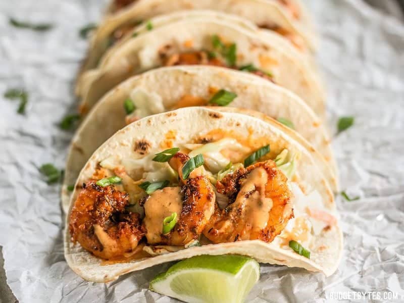 Close up front view of Blackened Shrimp Tacos drizzled with garlic lime sauce.