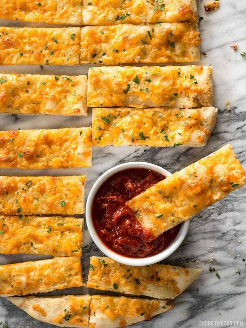 Overhead view of sliced Homemade Cheesy Garlic Bread with a dish of pizza sauce