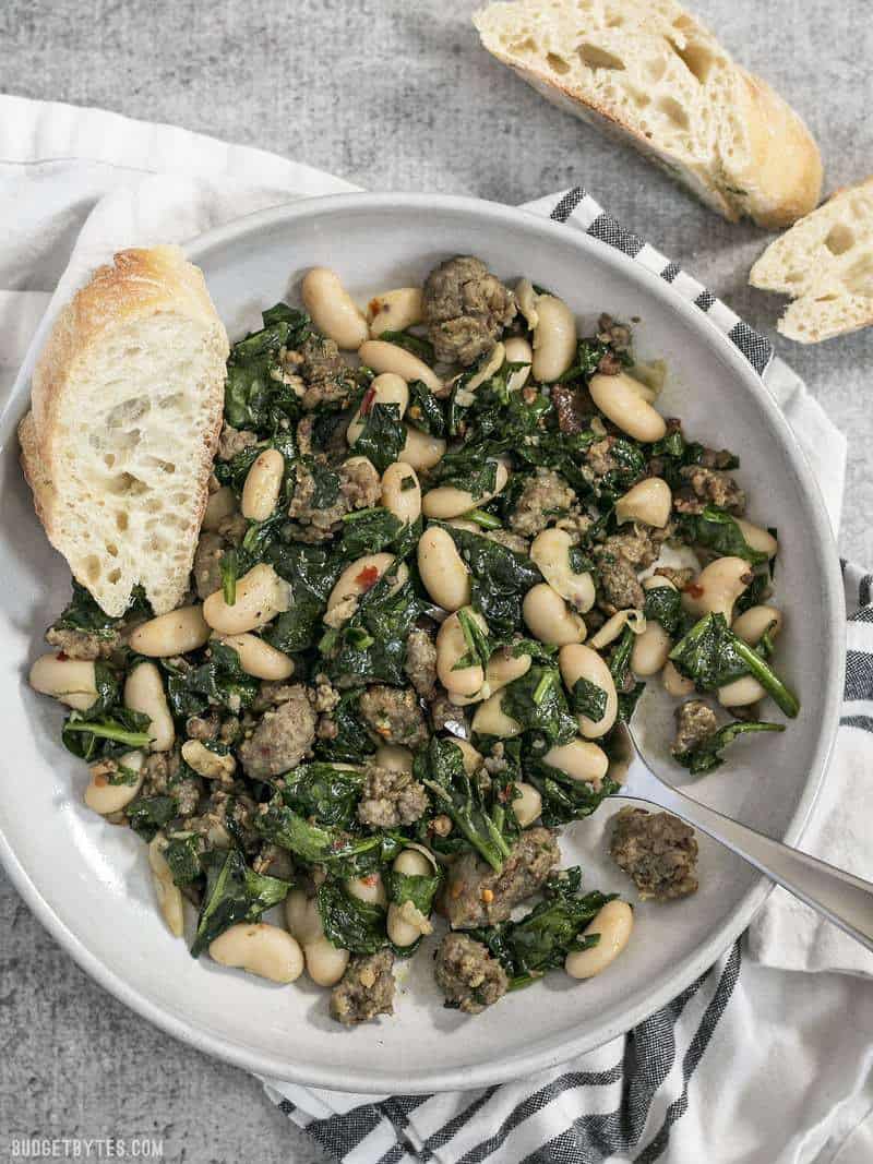 A bowl of Italian Sausage and White Beans with slices of baguette on the side