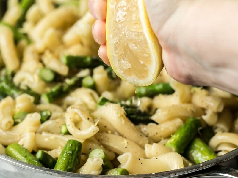 Lemon being squeezed over pasta