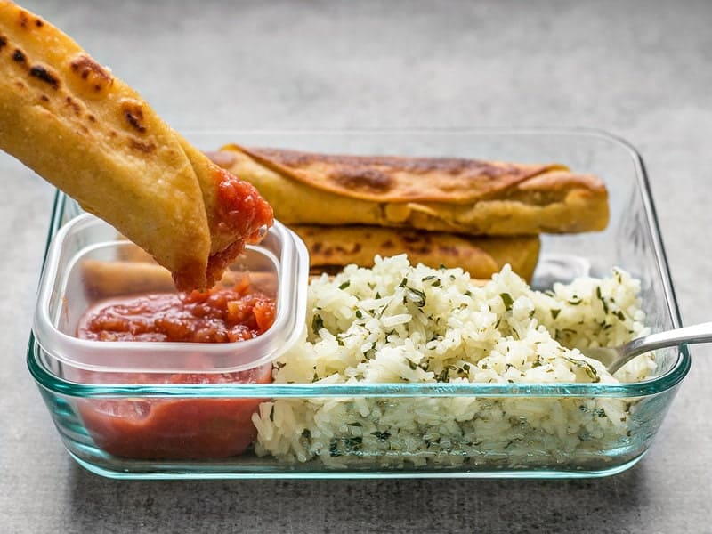 A Creamy Black Bean Taquito being dipped into salsa