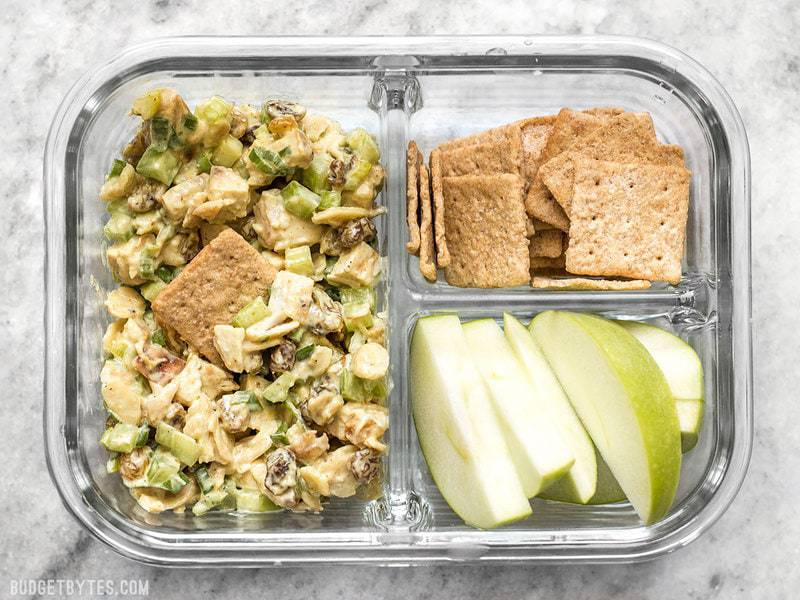 A single Curry Chicken Salad meal prep container with crackers and apples