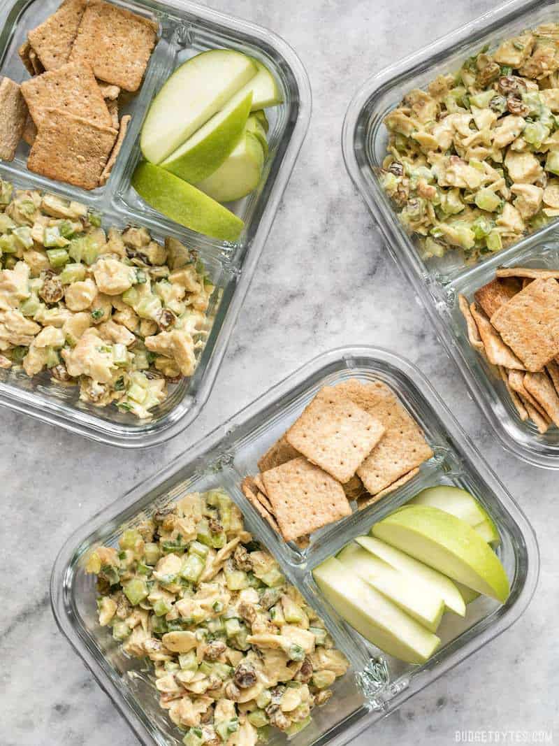 Curry Chicken Salad meal prep containers scattered on a surface