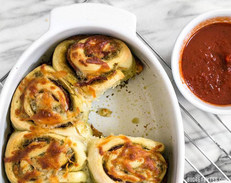 Close up of the casserole dish of Pesto Pizza Rolls with one missing