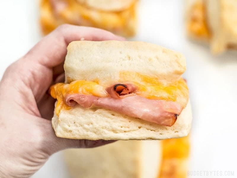 Close up of a hand holding a Ham and Cheese Biscuit