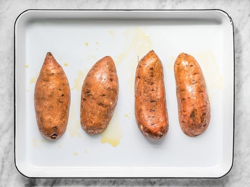 Oiled Sweet Potatoes facing cut side down on the baking sheet