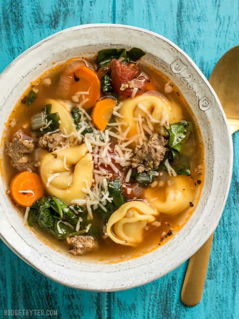 Overhead shot of a bowl of Sausage and Tortelloni soup with shredded Parmesan on top