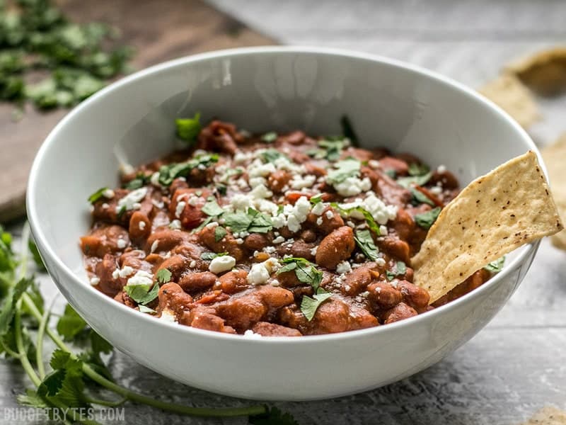 Side view of a bowl of Instant Pot Pinto Beans with chorizo. Topped with cheese and cilantro.