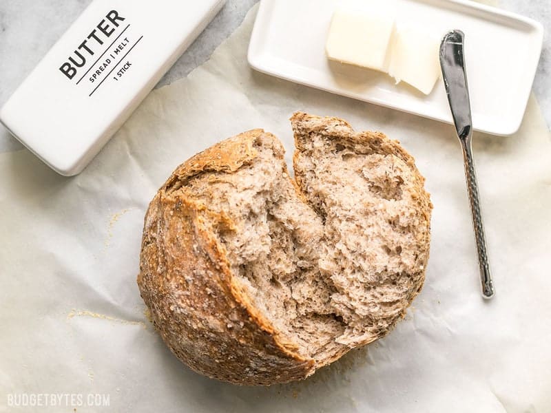 A loaf of Seeded No-Knead Bread next to butter