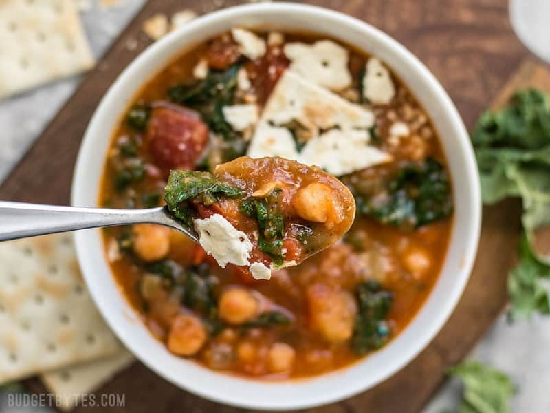 Close up of a spoonful of Smoky Potato Chickpea Stew with the bowl in the background.