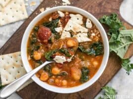 Overhead view of a bowl of Smoky Potato and Chickpea Stew with crumbled saltine crackers and a spoon in the middle