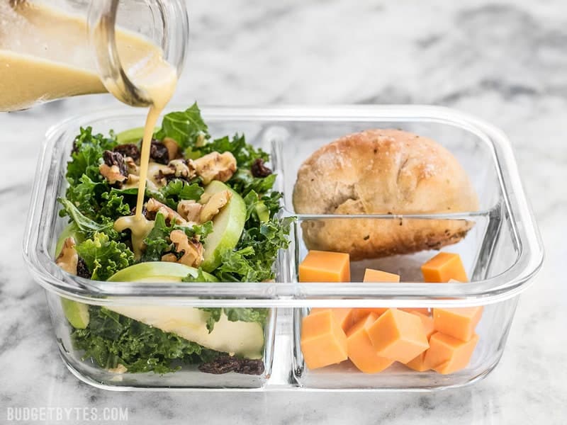 Dressing being poured on Apple Dijon Kale Salad 