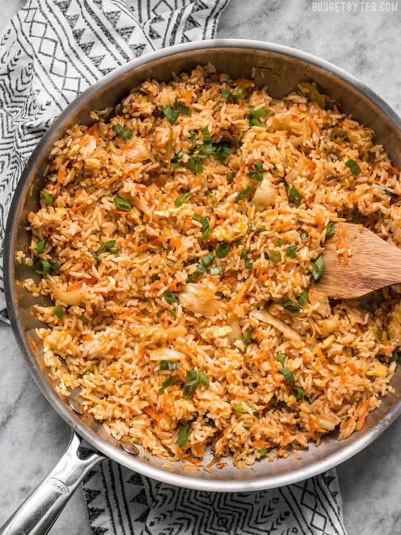 A skillet full of Kimchi Fried Rice with a wooden spatula