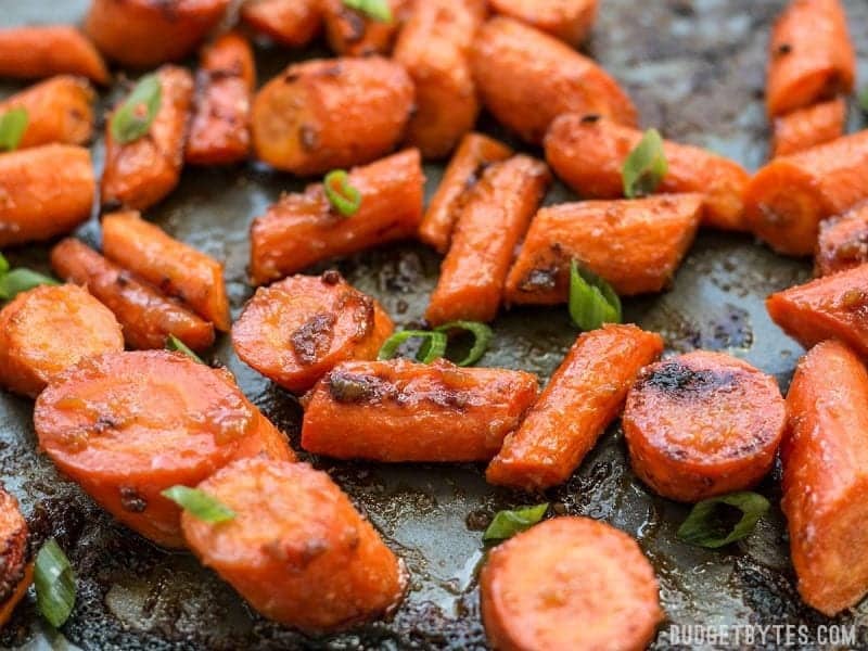 Close up of Maple Miso Roasted Carrots on the baking sheet with green onions