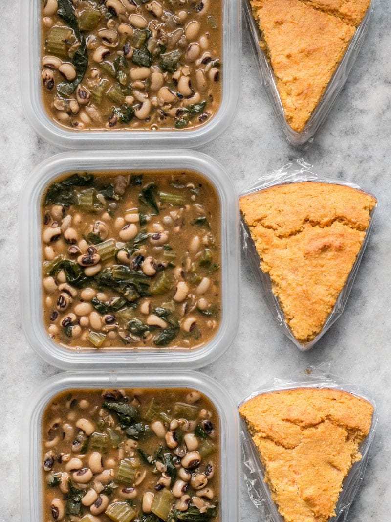 Three Black Eyed Peas Meal Prep containers in a row with cornbread slices on the side