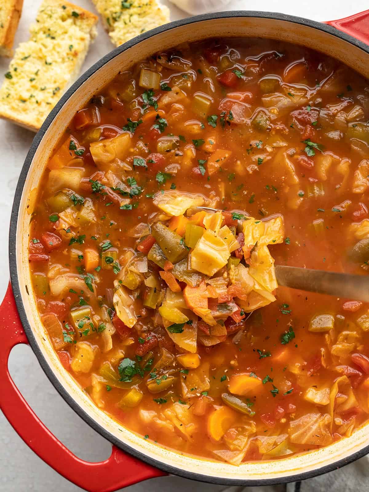 Overhead view of a pot of cabbage soup with a ladle