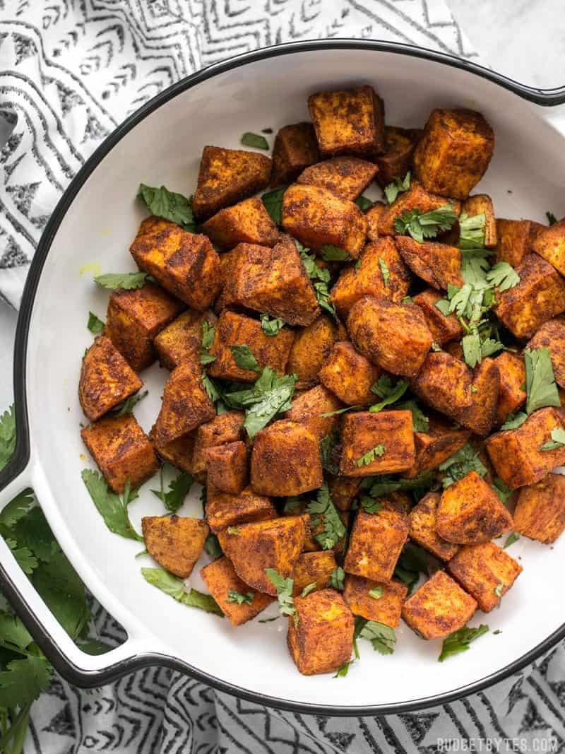 A casserole dish containing Moroccan Spiced Sweet Potatoes on a patterned napkin