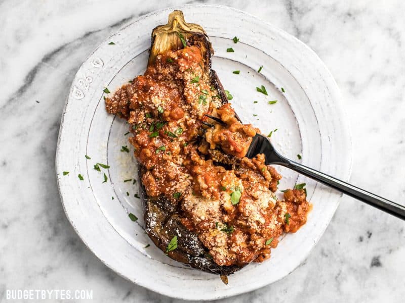 Roasted Eggplant with Meat Sauce on a white plate with a black fork scooping some up