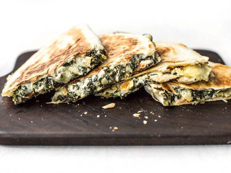 Sliced Spinach Artichoke Quesadillas on a cutting board