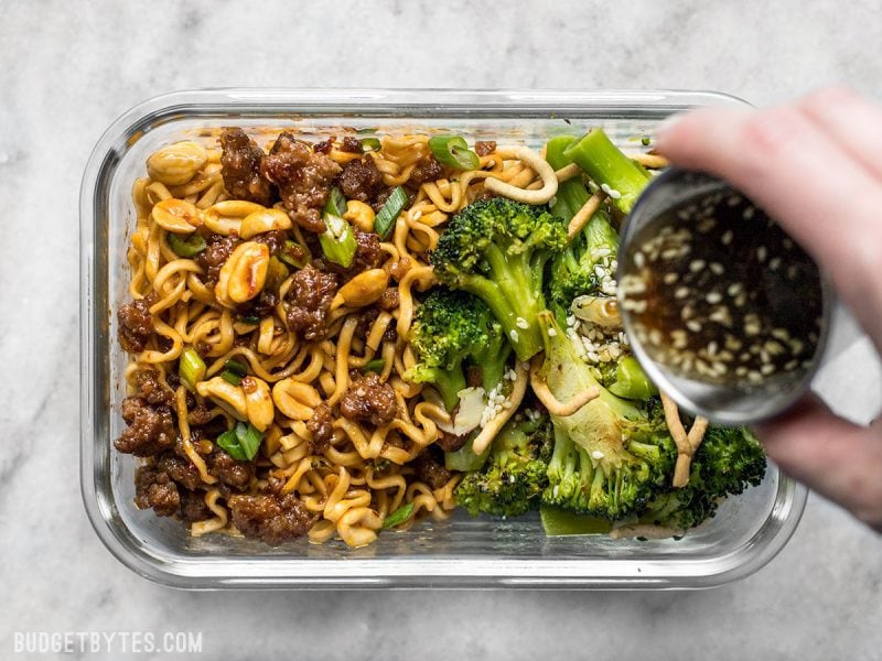 Dressing being poured onto Broccoli Salad in the Pork and Peanut Dragon Noodle Meal Prep 