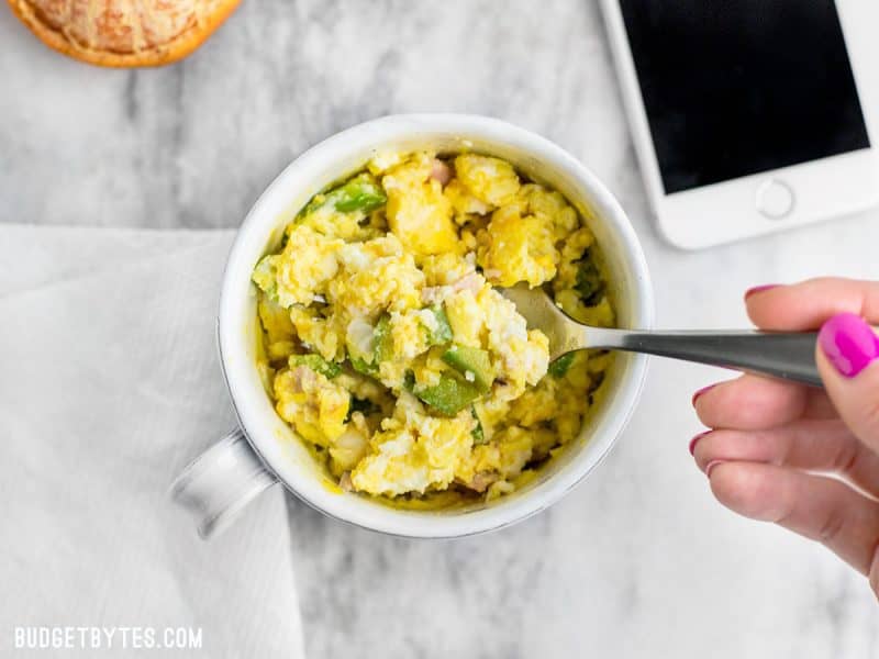Make Ahead Microwave Breakfast Scrambles are a fast, easy, and healthy breakfast when you’re short on time! BudgetBytes.com A Make Ahead Microwave Breakfast Scramble being eaten.