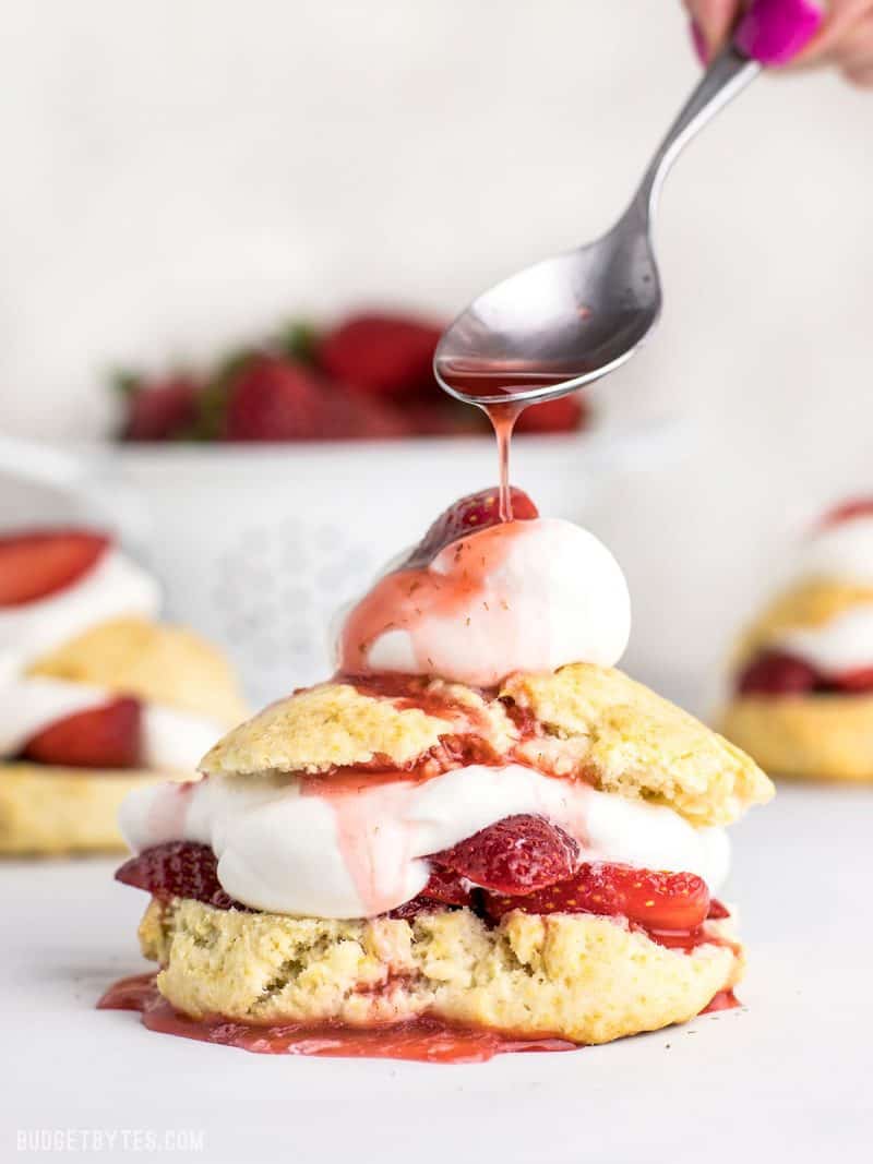 Strawberry syrup being drizzled over Strawberry Shortcake 