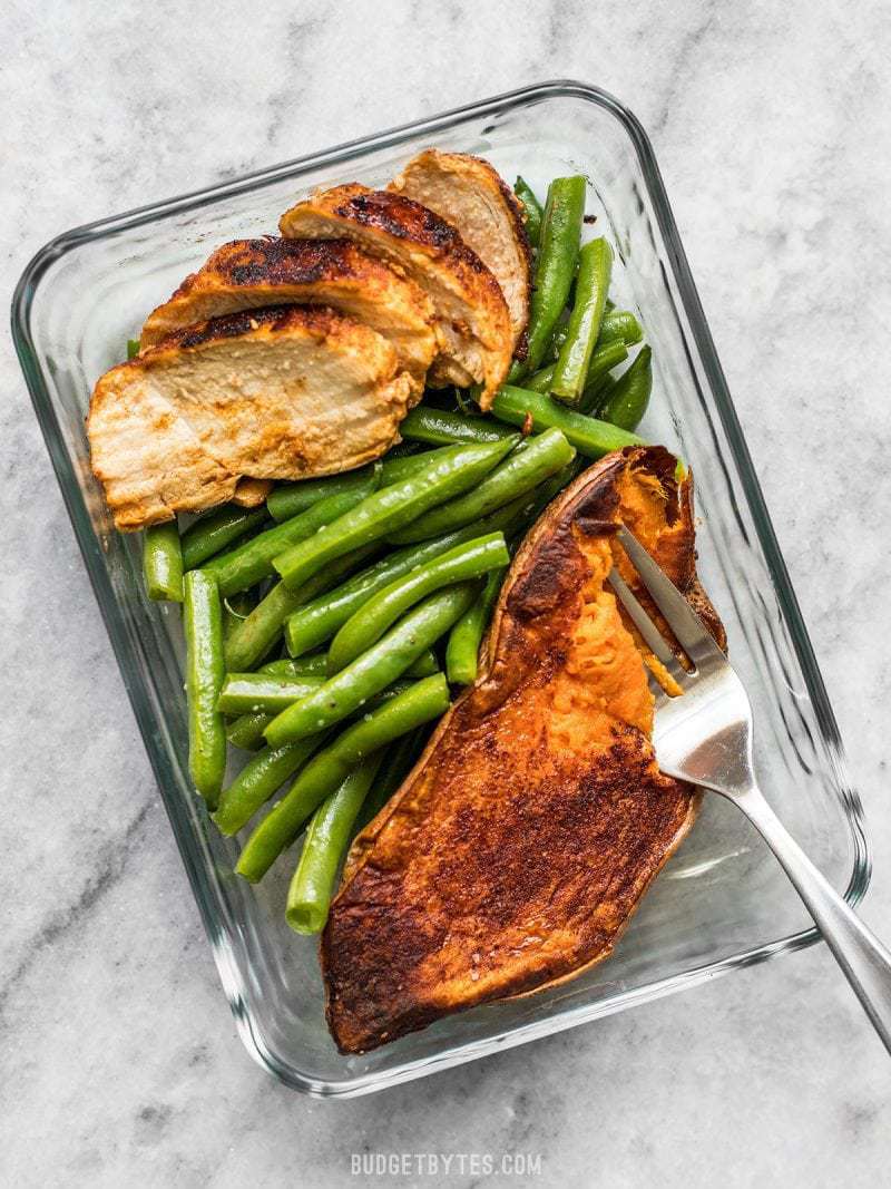 One meal prep container with Smoky Chicken and Cinnamon Roasted Sweet Potatoes and a fork