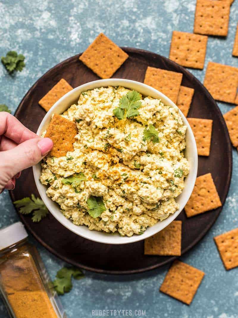 A cracker being dipped into Curried Tofu Salad 