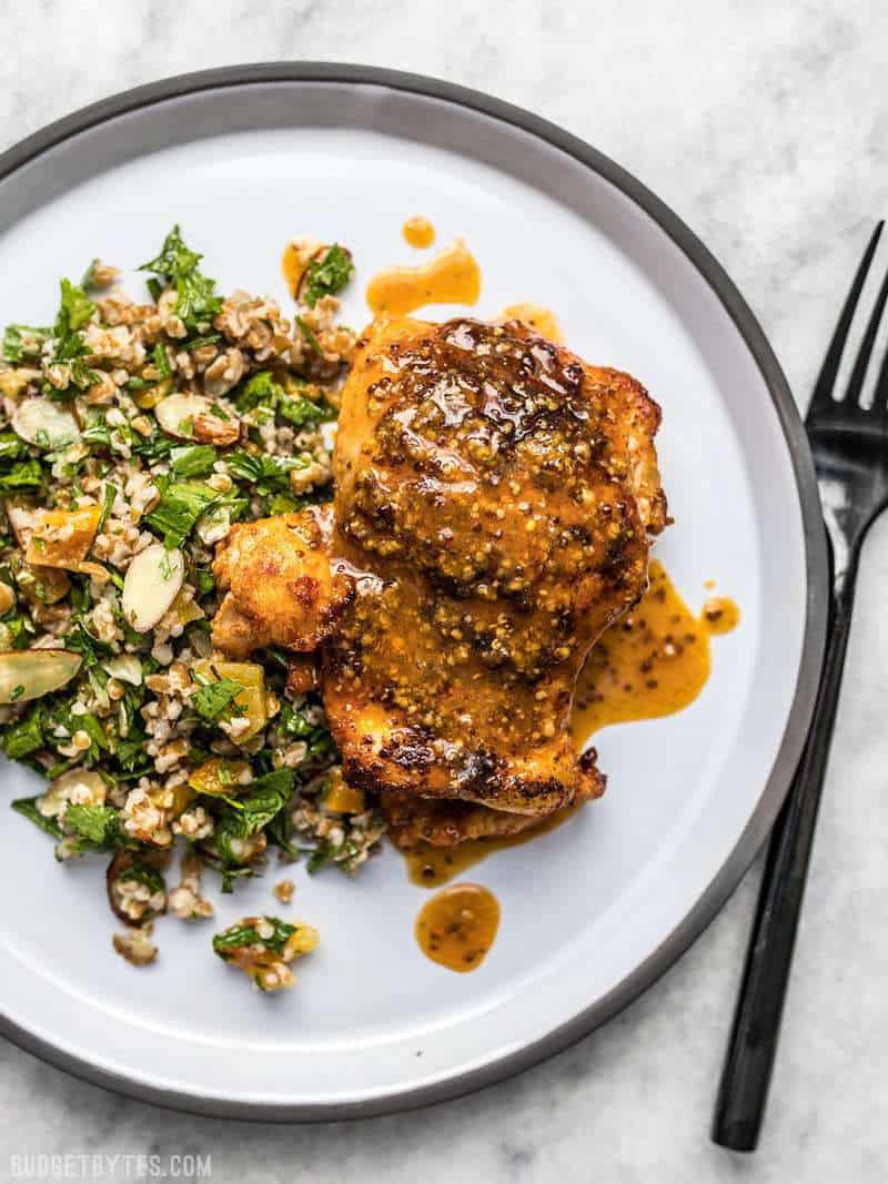 A piece of Honey Mustard Chicken on a white plate with parsley salad.