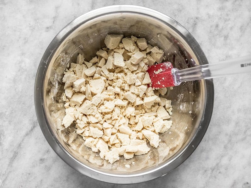 Chopped tofu coated with cornstarch in a bowl with a spatula