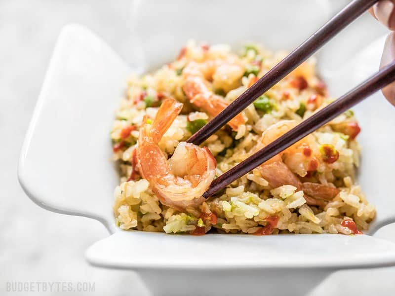 Close up of chopsticks picking up a piece of shrimp out of the container of Teriyaki Shrimp and Rice