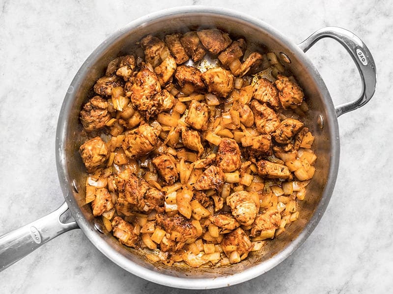 Onions added to skillet with cooked chicken and Cajun seasoning.