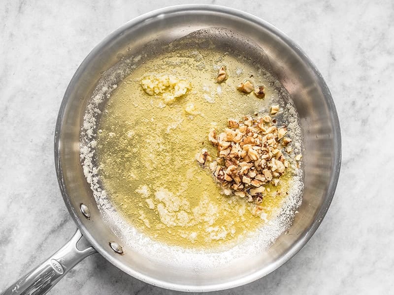 Chopped walnuts and garlic added to melted butter in the skillet