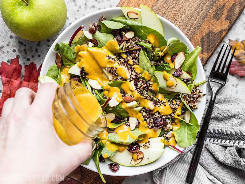 Lemon Turmeric Dressing being poured onto an Autumn Quinoa Salad