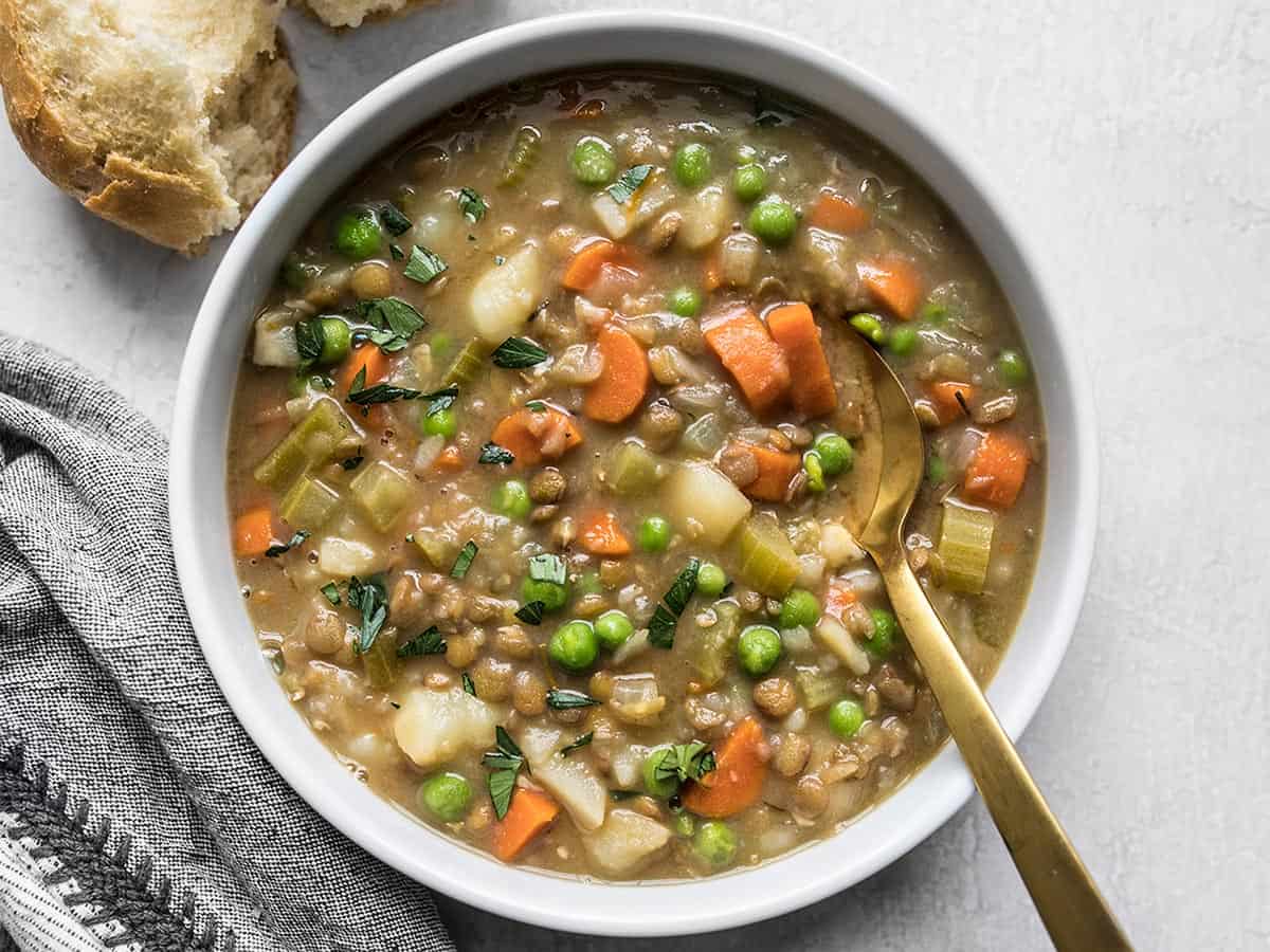 Overhead view of a bowl of lentil stew with a gold spoon in the center.