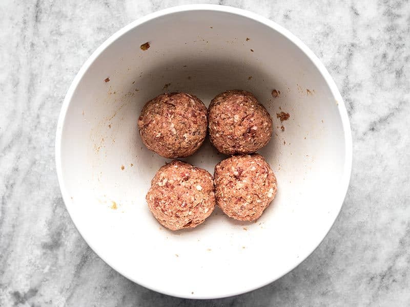 Shaped uncooked meatballs in a white bowl