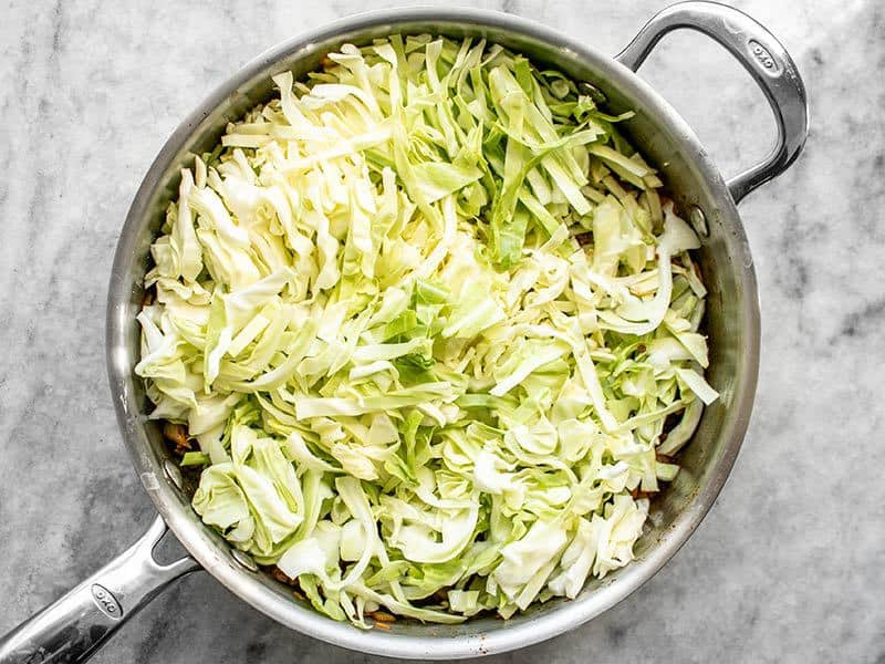 Shredded cabbage added to cooked beef in the skillet