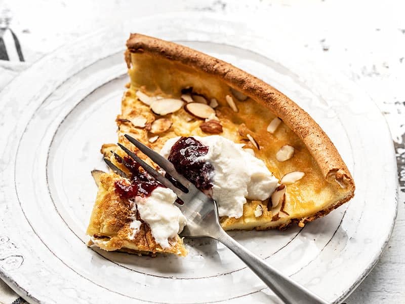 One slice of Almond Dutch Baby with Ricotta and Jam being eaten.