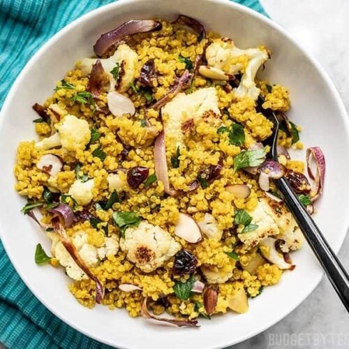 A bowl of Roasted Cauliflower and Quinoa Salad on a teal napkin.