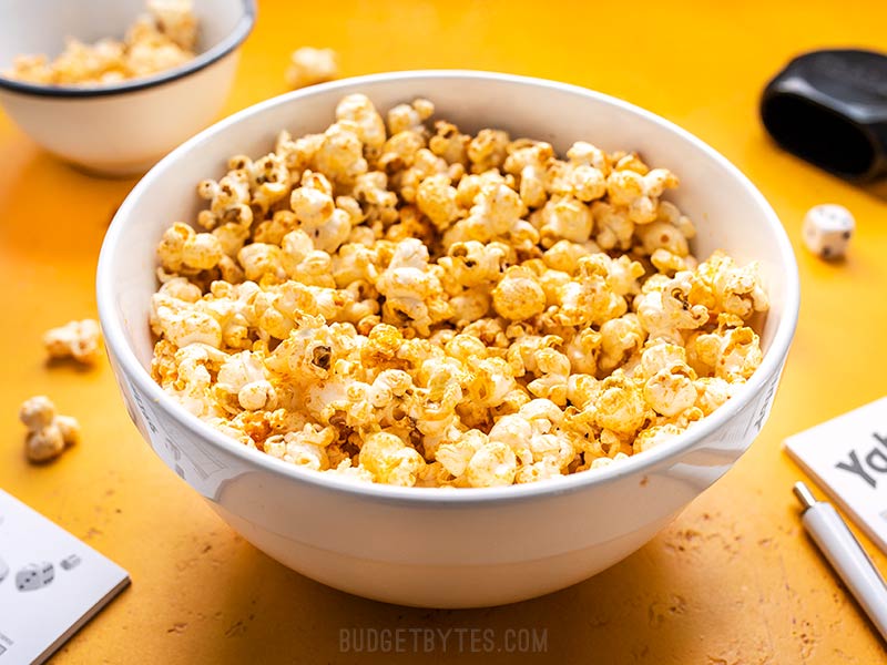 Front view of a bowl of Sriracha Nooch Popcorn on a yellow background.