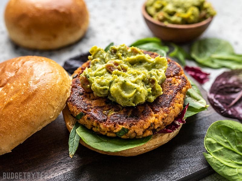 A Cajun Salmon Burger topped with guacamole without the top bun.