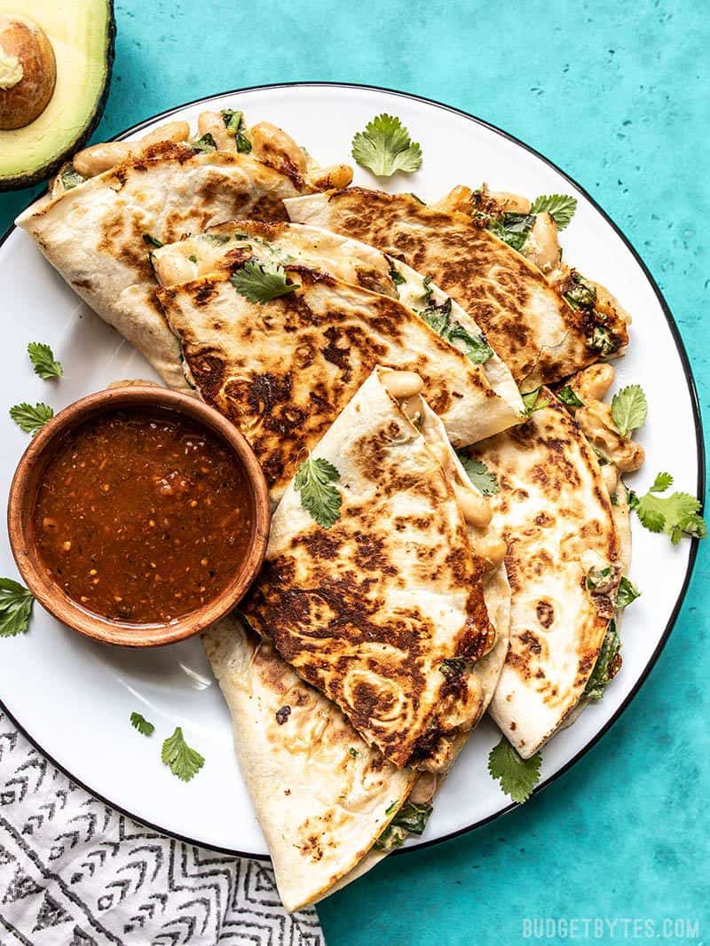 A plate full of Creamy White Bean and Spinach Quesadillas with a dish of red salsa