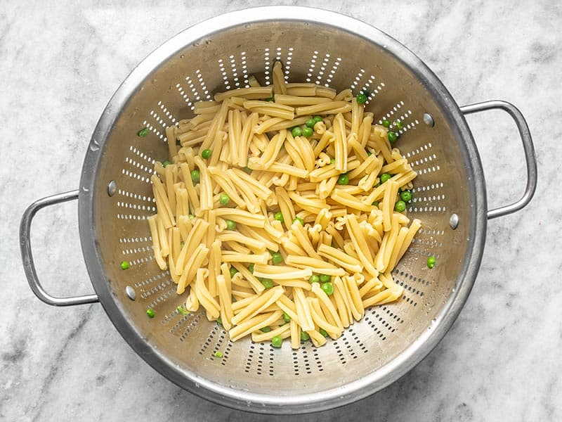 Boiled Pasta and Peas draining in a metal colander