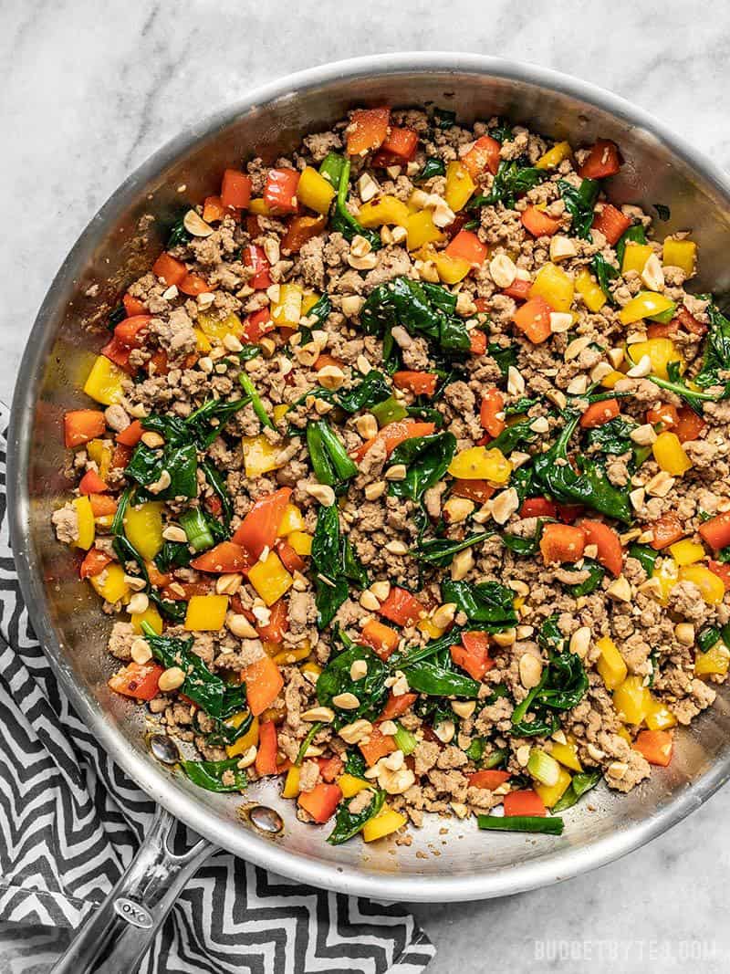 A skillet full of Ground Turkey Stir Fry with a striped napkin on the side