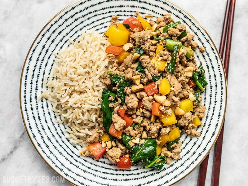 A patterned plate with Ground Turkey Stir Fry and Brown Rice, chopsticks on the side