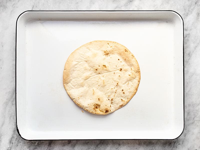 Par-baked flour tortilla on the baking sheet.