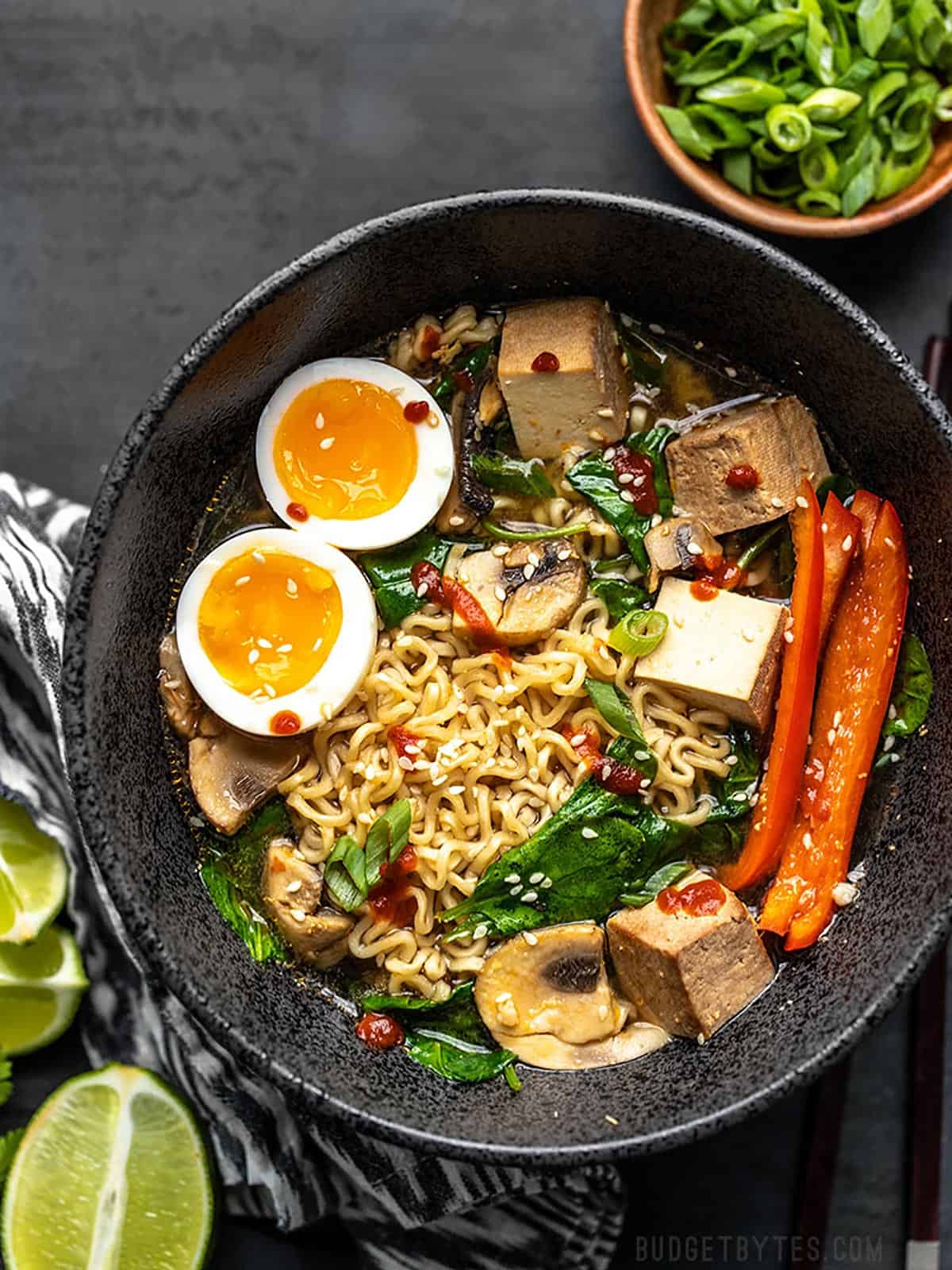 Overhead view of a bowl of instant ramen with extra ingredients added like egg, tofu, and vegetables.