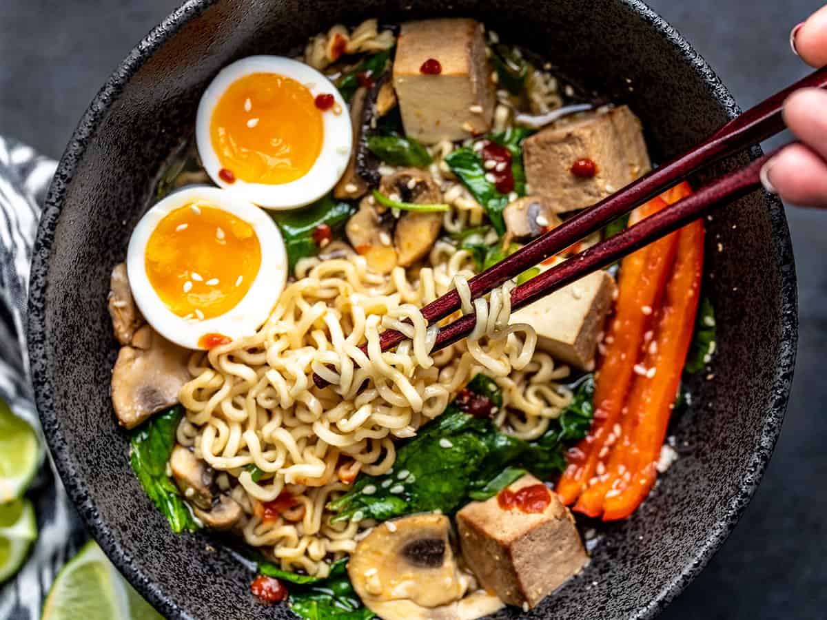 Close up overhead view of a bowl of upgraded instant ramen with chopsticks twirled into the noodles. 